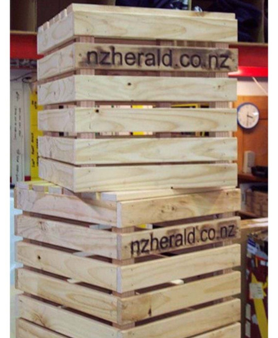 Stacked pine timber crates with a newspaper's web address burnt into the slats, used as a branded display
